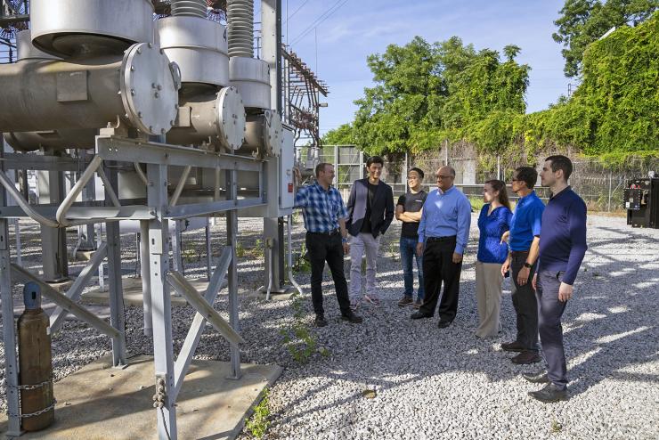 The team examining a high-voltage circuit breaker at an electrical substation. The greenhouse gas, sulfur hexafluoride (SF6), is