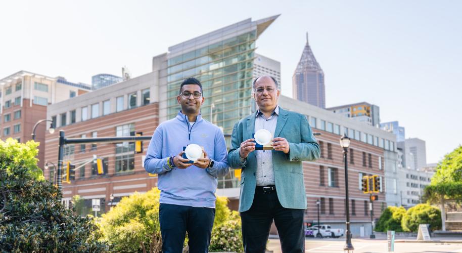 Professor Emmanouil “Manos” Tentzeris and Ph.D. student Marvin Joshi hold a lens‑enabled backscatter system that could support battery‑free wireless communication across future smart city infrastructure.