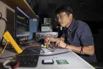 GTRI researcher Paul Jo GTRI researcher Paul Jo checks an RF test board with FCBGA packaged single-channel T/R module chips. (Credit: Sean McNeil, GTRI)