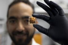 male researcher wearing a black glove holds a solar cell prototype