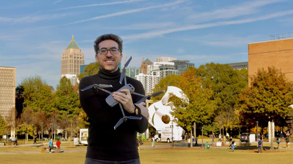 Tarek Rakha on the Georgia Tech campus holding a drone in his arms.