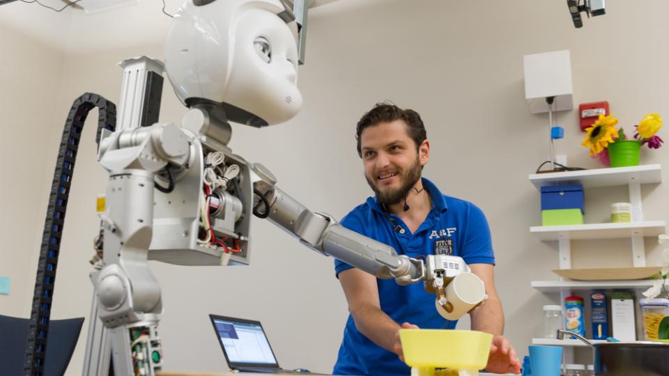 Man working with robot pouring from a cup